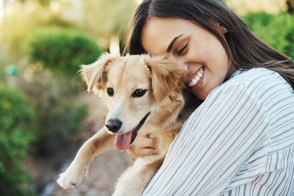 Smiling woman hugging her dog.